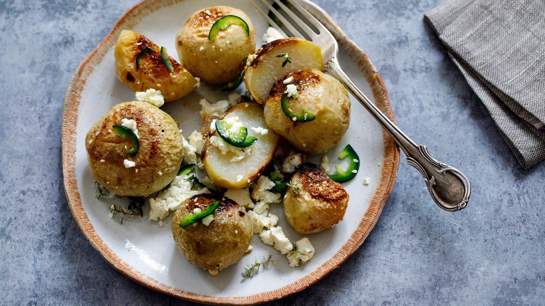 Geschmorter Kohlrabi mit Feta und Kräutern auf einem weißen Teller.